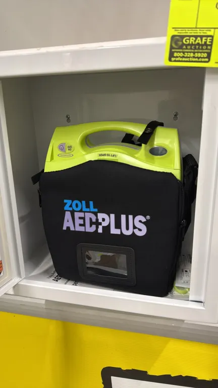 Zoll AED Plus automated external defibrillator. Includes carrying case and Cintas metal wall-mount storage cabinet with windowed door.