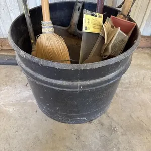 Plastic pot with brooms, dustpan, machete, ax.