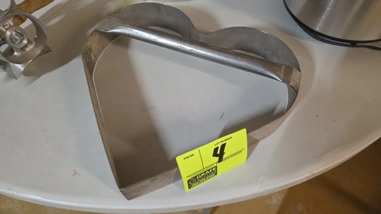 Stainless steel heart-shaped dough cutter. Features integrated crossbar handle. Dimensions: 14" x 14" x 2-1/4".