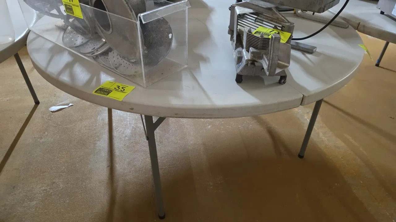 Round poly folding table. Features a molded plastic top with a fold-in-half design and folding metal legs. 60"Dia. Contents not included.