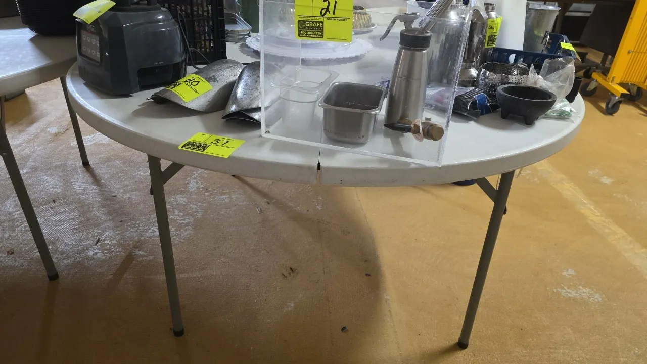 Round poly folding table. Features a fold-in-half molded plastic top and folding metal legs. 60"Dia. Contents not included.