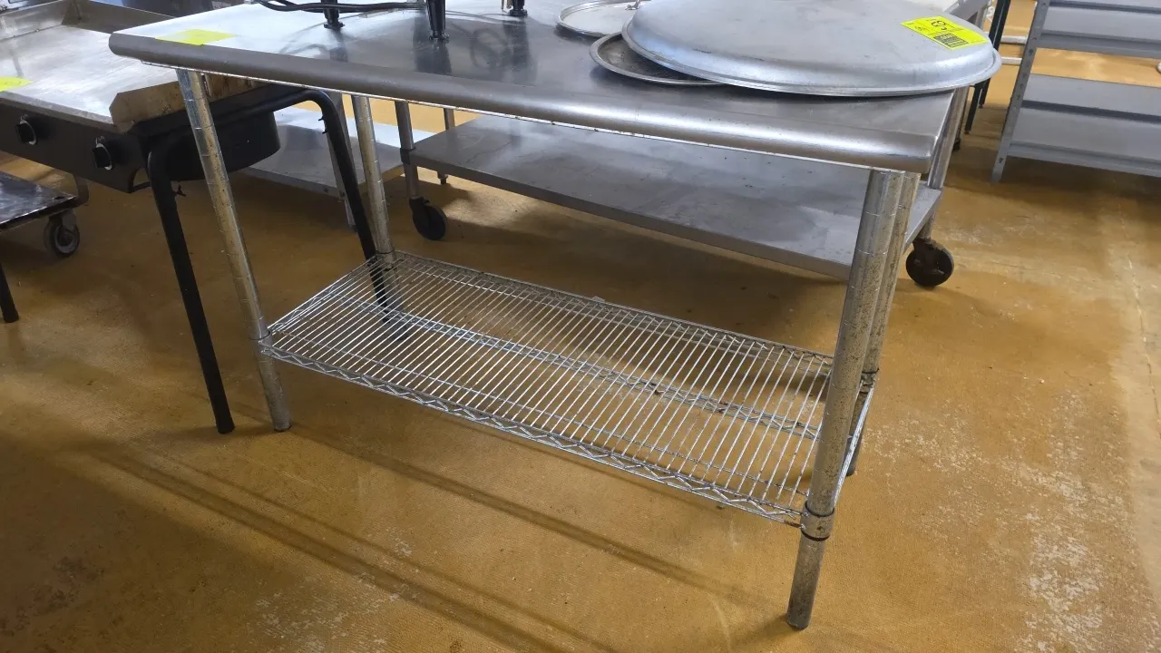 Stainless steel work table. Features a bullnose front edge and an adjustable wire undershelf. 49.5"L x 24"W. Mounted on tubular metal legs. Contents n