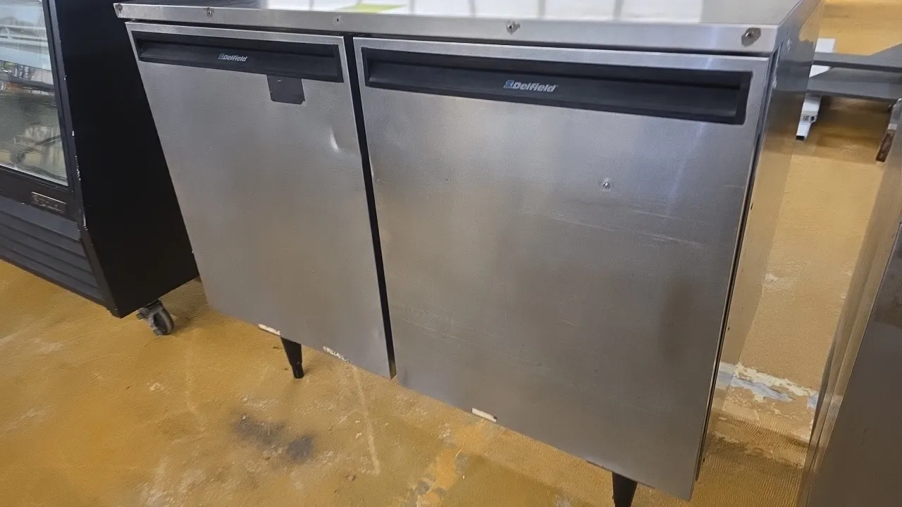 Delfield UC4048 self-contained undercounter refrigerator. Features stainless steel construction, 2 solid doors, and wire shelving. 48"L. S/N: 402718-T