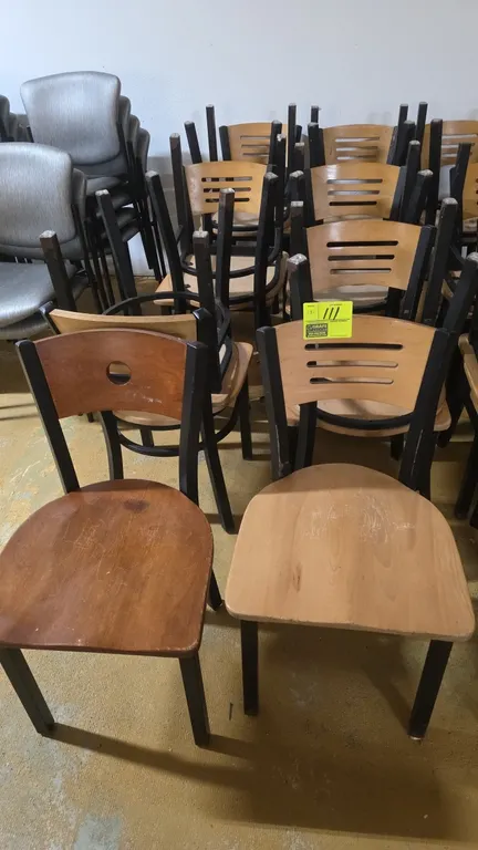 Restaurant chairs. Features black metal frames, contoured wood seats, and horizontal slat backrests. Includes one chair with dark wood finish and circ