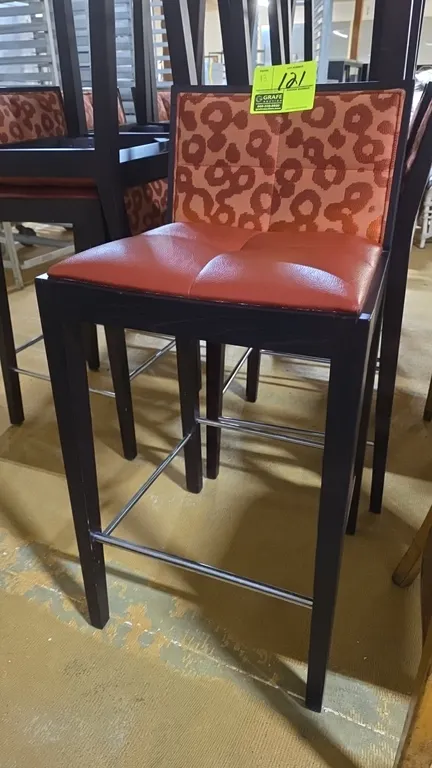 Wood frame bar stools. Features dark wood frames, tufted rust faux-leather padded seats, patterned fabric upholstered backrests, and chrome footrest s