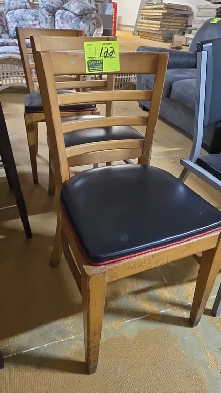Wood frame ladder-back dining chairs. Features curved ladder-back design, natural wood finish, and black vinyl padded seats with red accent piping.
