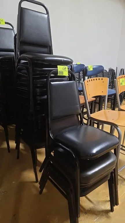 Stackable chairs. Features black vinyl upholstered padded seats and backrests with integrated top grab handles, black metal frame construction, and st