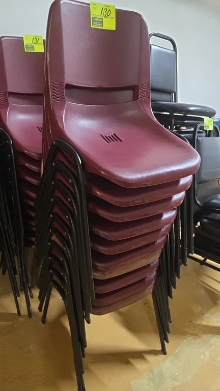 Polypropylene stackable chairs. Features burgundy molded plastic shells with integrated handle cutouts and vented seats. Mounted on black tubular meta
