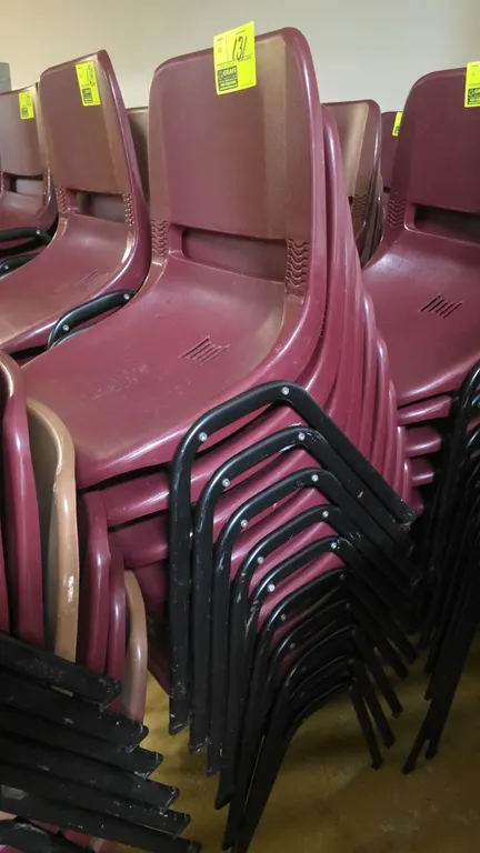 Poly stackable chairs. Features molded burgundy plastic seats with vented slots and integrated rear handle. Mounted on black tubular metal frames.