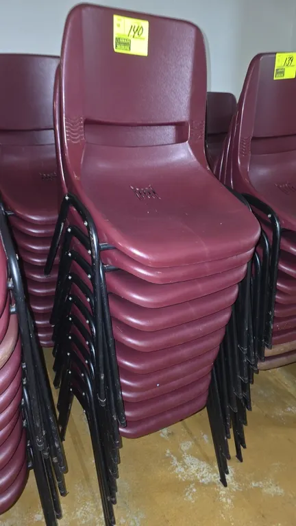 Poly stackable chairs. Features burgundy molded polypropylene shells with integrated rear handle cutouts and seat ventilation slots. Mounted on black