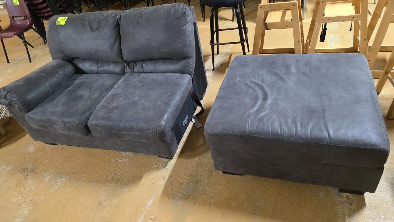 One-arm sectional loveseat with matching ottoman. Features dark gray microfiber upholstery, pillow-top armrest, sectional connector bracket, and squar