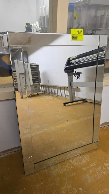 Beveled glass wall mirror. Features a mirrored border frame. 30" x 42". Note: Glass is cracked on the bottom left.