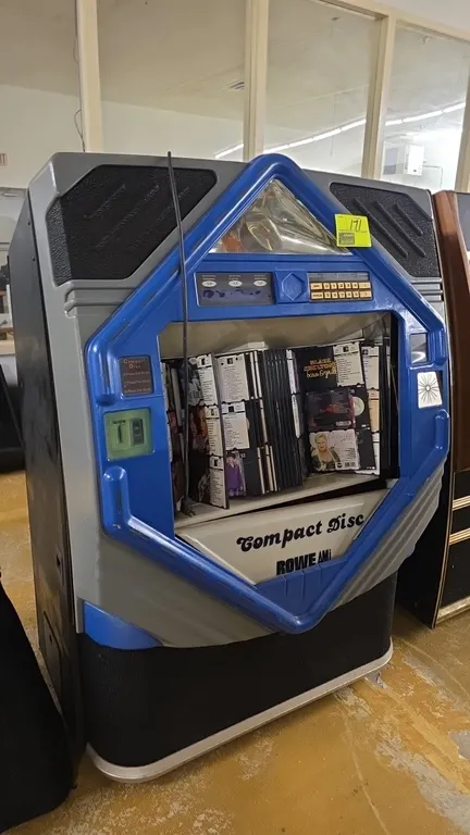 1994 Rowe AMI CD-100E commercial CD jukebox. Features push-button controls, flip title rack display, and coin mechanism. S/N: 6242. Electrical: 120V,