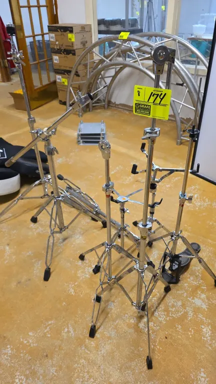 Assorted drum hardware stands. Features chrome-plated construction. Includes snare stands, a hi-hat stand with foot pedal, and cymbal boom and straigh