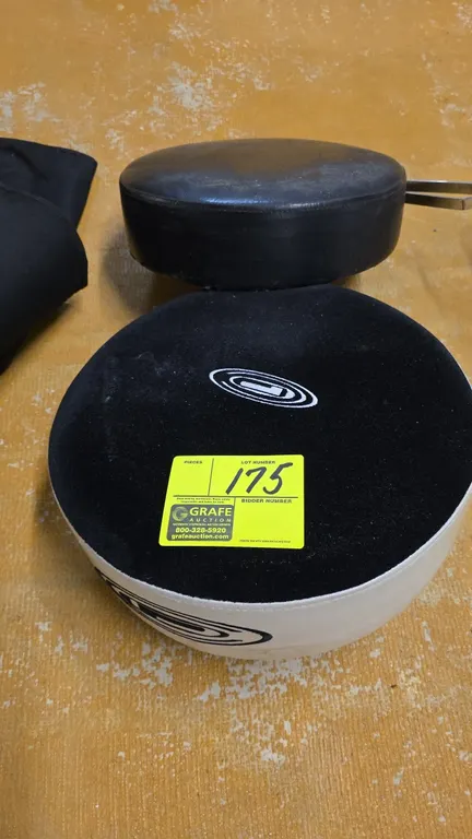 Assorted stool seat cushions. Includes (2) round padded seat tops with underside mounting brackets, featuring one black vinyl cushion and one two-tone