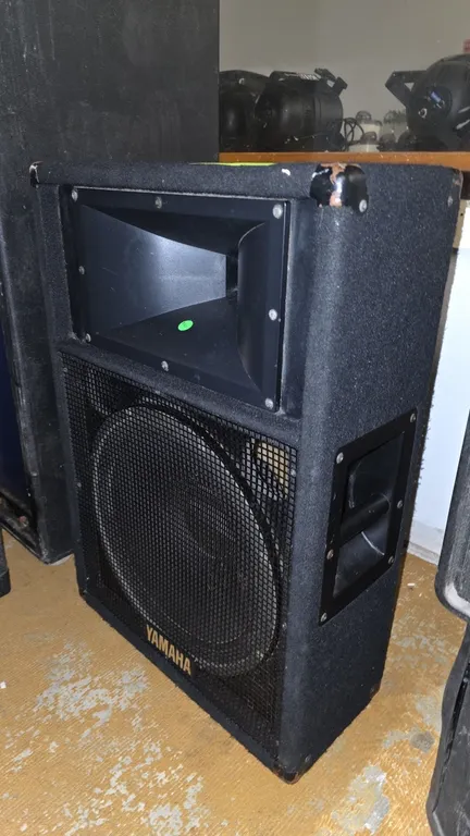Yamaha SM15IV loudspeaker. Features a 15" woofer with protective metal grille, high-frequency horn, black carpet-covered enclosure, recessed carry han