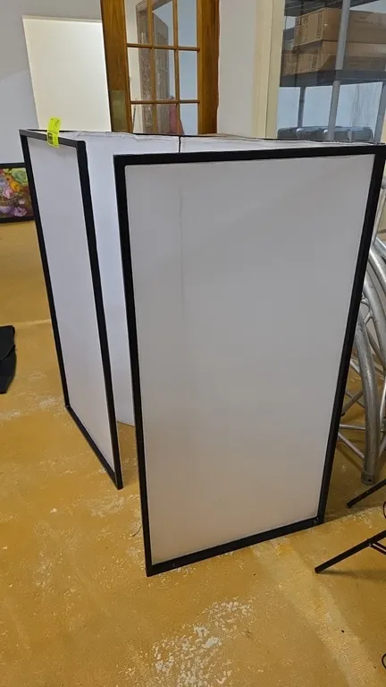 Portable 4-panel DJ facade. Features folding black metal frame with white scrim panels. Dimensions: 24" x 46" per panel.
