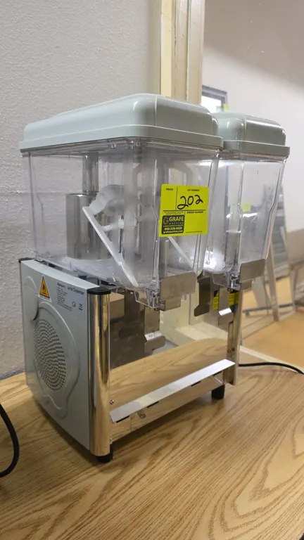 Adcraft JD-2 refrigerated juice dispenser. Features (2) clear plastic bowls with lids, stainless steel push-lever dispensing handles, paddle agitation
