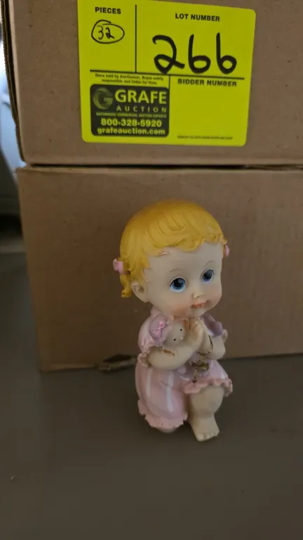 A Collection of Bona Idea "Baby w/Bear" Figurines. (Bona Idea Inc.) A 32-piece set of painted figurines depicting a kneeling praying baby in pink hold