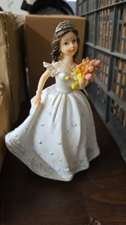 Bona Idea PY252B 8" XV dolls with flower bouquet. Features white dress with silver glitter accents, tiara, and bouquet. 8"H. Includes (15) individuall