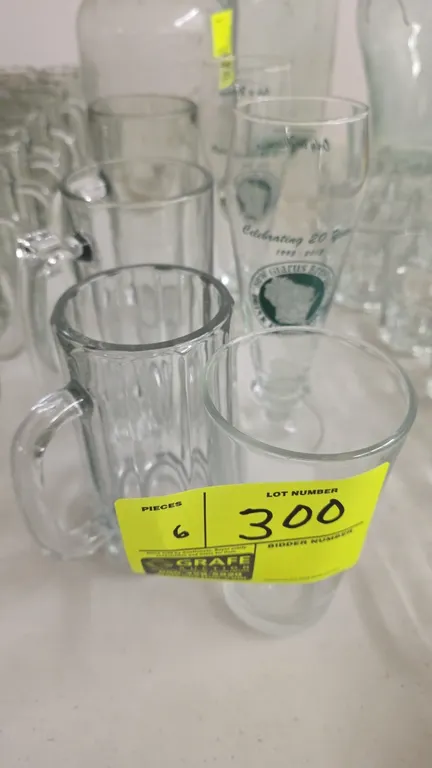 Assorted beer and beverage glassware. Includes (2) New Glarus Brewing Co. 20th Anniversary footed pilsner glasses, (3) handled glass beer mugs in asso