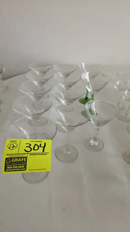 Assorted martini glasses. Includes (12) pieces in various sizes and styles, featuring traditional clear stems and green twist-stem designs.