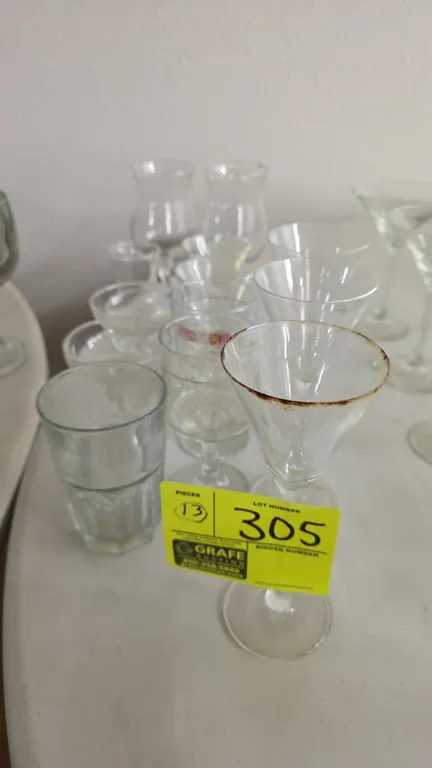 Assorted glassware lot. Includes (13) pieces of various sizes and styles including stemmed cocktail glasses, hurricane glasses, dessert coupe glasses,