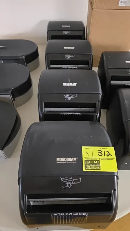 Monogram automatic hands-free roll towel dispensers. Features black plastic housing, touchless motion sensor operation, and front paper exit. Designed