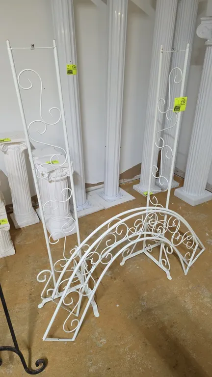 White metal wedding archway. Features decorative scrollwork and a 3-piece modular design including two vertical upright sections and an arched top pie