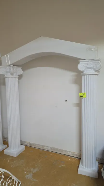 3-piece white polyethylene colonnade wedding arch set. Includes (2) 6'H fluted columns with Ionic-style capitals and square bases, and (1) arched top
