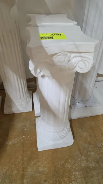 White lightweight plaster pedestal columns. Features fluted shafts, decorative Ionic-style scroll capitals, and square bases. 28½"H.