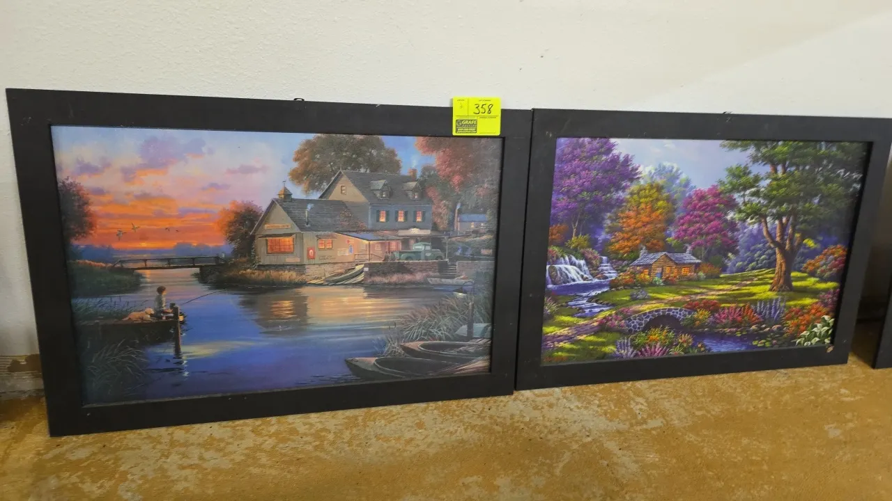 Framed wall decor prints. Features scenic landscape artwork in black frames, including a lakeside scene with boathouse at sunset and a cottage garden