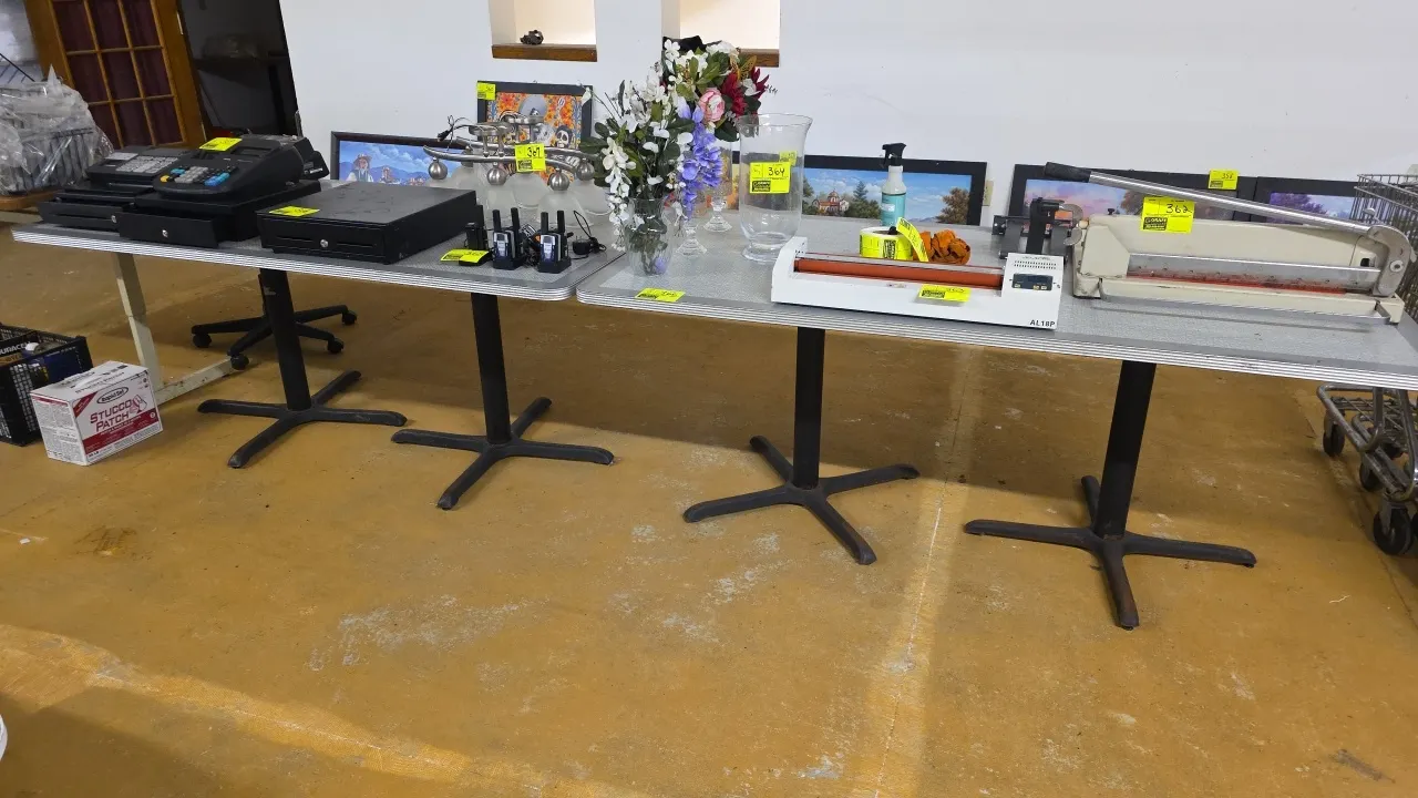 Laminated dining tables. Features gray patterned laminate tops with ribbed aluminum edge banding. Each table is mounted on dual black metal X-style pe