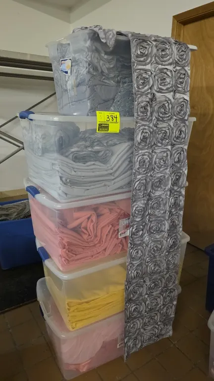 Sterilite plastic storage totes with assorted event linens. Includes (5) lidded clear plastic totes containing rosette table runners, tablecloths, and