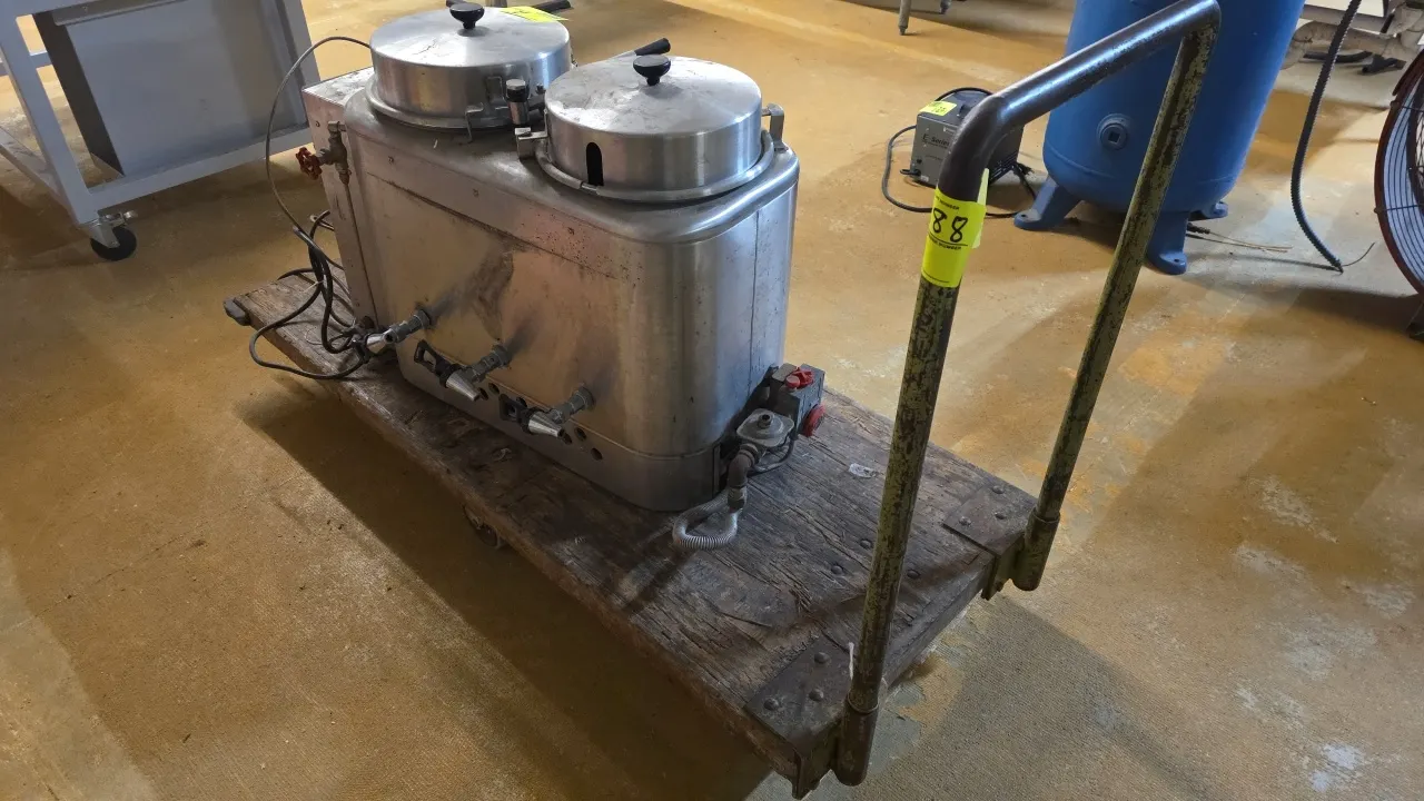 Flatbed platform cart. Features a wood deck, tubular steel push handle, and protective corner bumpers. 60" x 25". Mounted on casters. Contents not inc