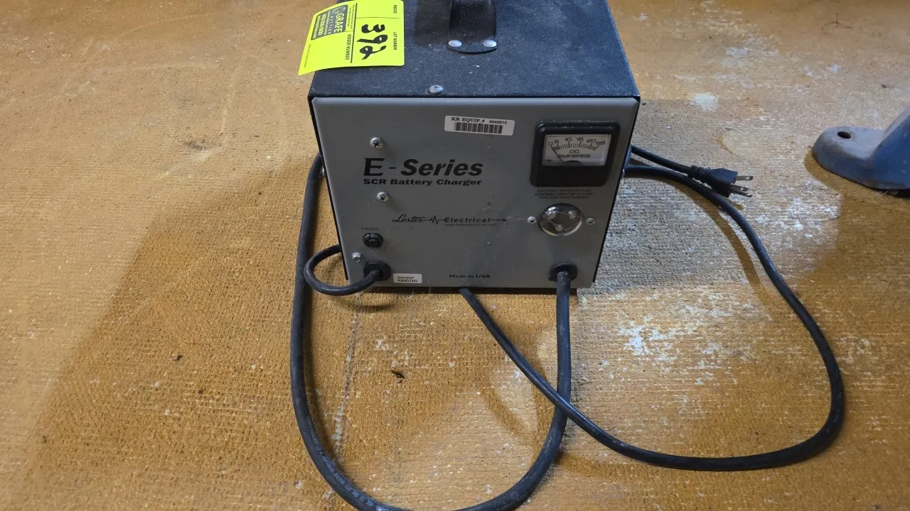 Lester Electrical 56383078 E-Series SCR industrial battery charger. Features an analog DC ammeter, top carry handle, and battery connector cable. Outp