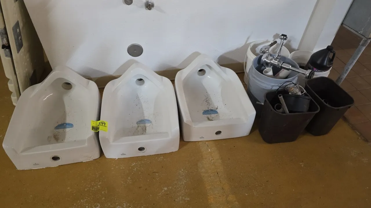 Gerber urinals. Features white vitreous china construction and wall-hung mounting. Includes assorted plumbing hardware, flush valves, and fittings.