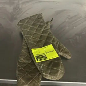 Pair of quilted commercial oven mitts. Features heat-resistant fabric construction and integrated hanging loops.