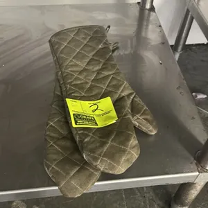 Pair of quilted oven mitts. Features heat-resistant fabric construction and hanging loops. Table not included.