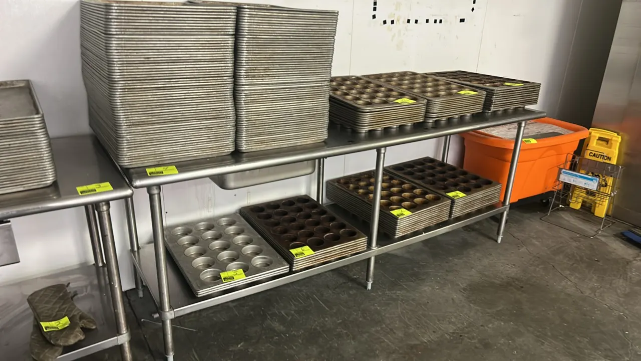 Stainless steel work table. Features a stainless steel undershelf. 96" x 30". Mounted on (6) tubular legs with adjustable bullet feet. Contents not in