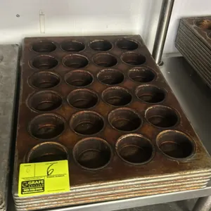 Commercial 24-cup metal muffin pans. Features a 24-cavity layout arranged in a 4 x 6 pattern with wire-reinforced rims.