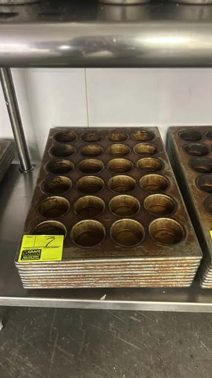 24-cup metal muffin pans. Features commercial metal construction arranged in a 4 x 6 cavity configuration with wire-reinforced rims.