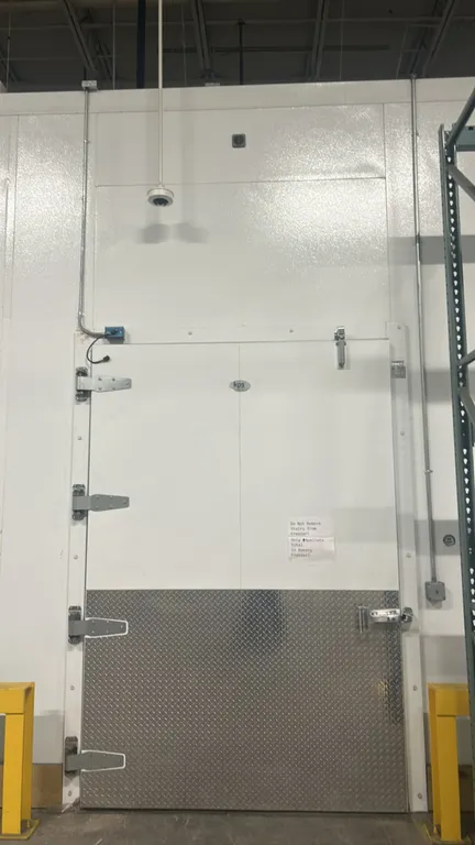KPS walk-in freezer. Features foam insulated panels, Witt 3-fan evaporator coil, interior overhead lighting, strip curtains, and a pallet-sized hinged