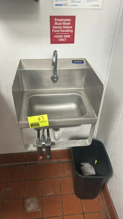 Amtekco stainless steel handwashing sink. Features knee-operated valve controls, gooseneck faucet, and integrated side splashes. Includes Kimberly-Cla