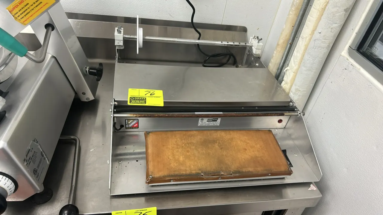 Heat Seal 625A stretch film overwrapper. Features stainless steel construction, heated sealing plate, and film roll cradle. S/N: GG21100075. Electrica