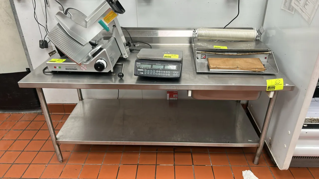 Win-Holt stainless steel work table. Features a rear backsplash, stainless steel undershelf, under-table pan slide, and tubular legs with adjustable b