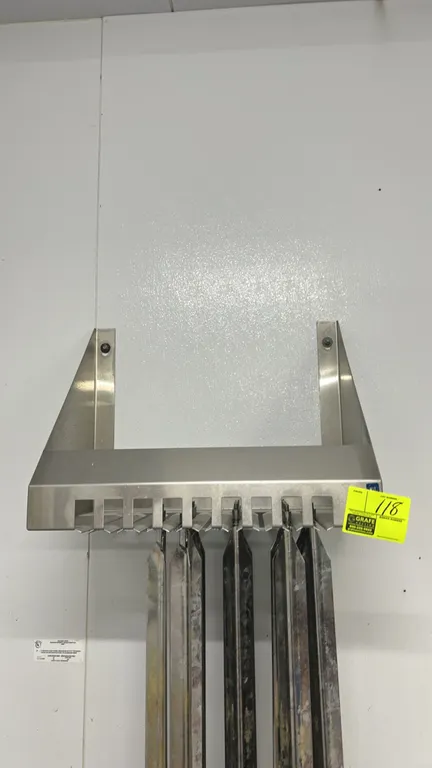 Stainless steel wall-mounted rotisserie skewer rack. Features slotted storage design and includes rotisserie spits as shown. NSF certified. Designed f