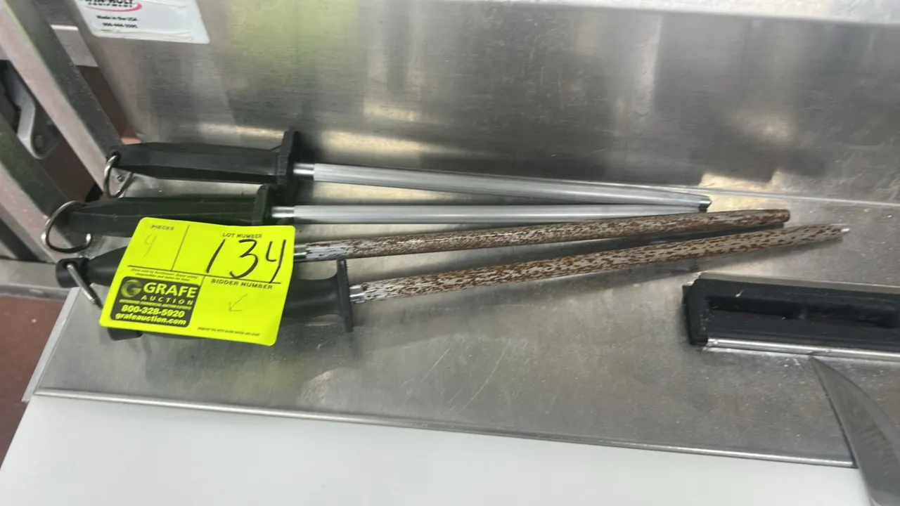 Stainless steel knife sharpening steels. Features molded black plastic handles with integrated hanging rings. Note: Two units exhibit heavy rust.