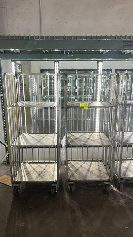 Metal multi-tier portable carts. Features 3-tier design with vertical slat sides and solid metal deck shelves. 26" x 25". Mounted on casters.