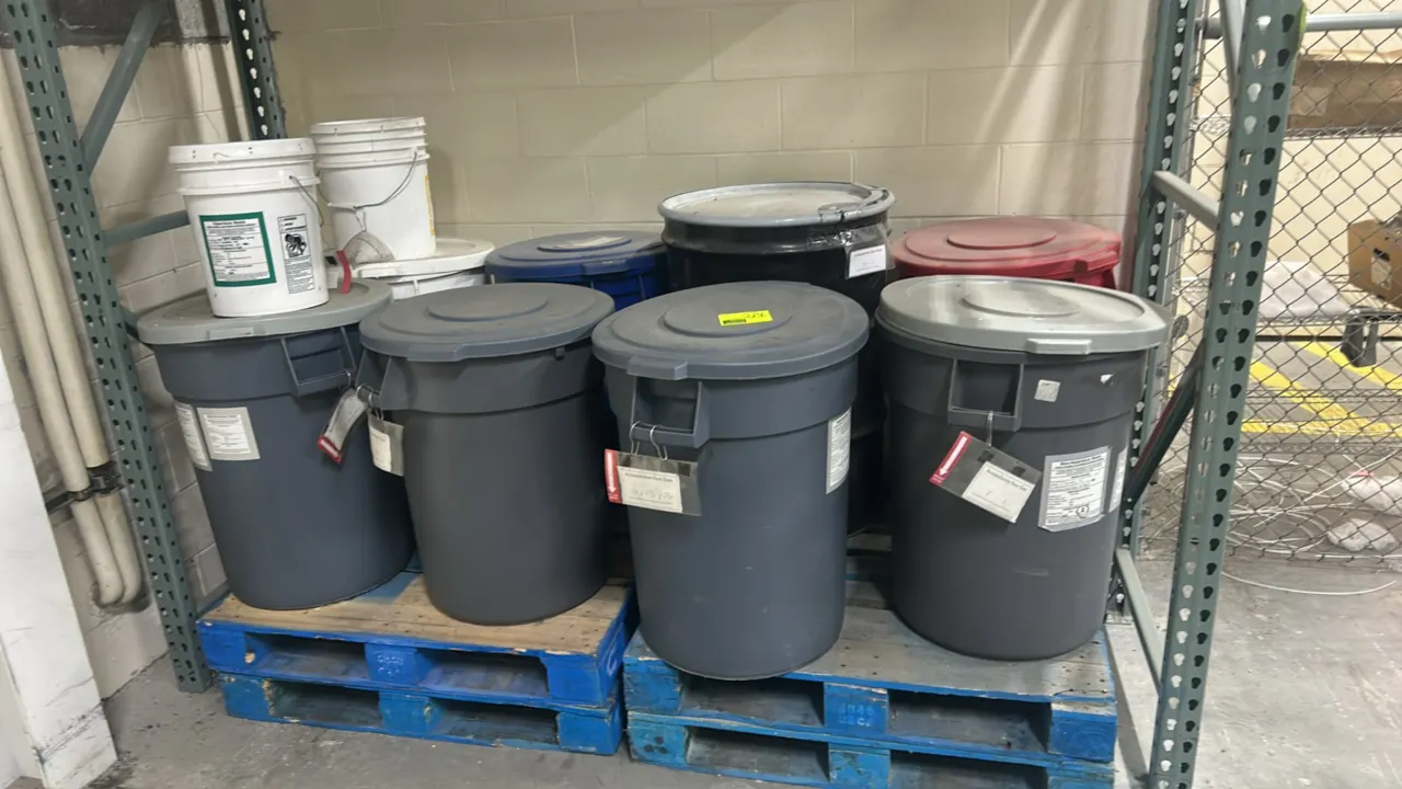 Polyethylene circular trash bins and (1) metal drum. Includes (6) poly trash cans with lids in gray, blue, and red, and (1) metal barrel with clamp ri